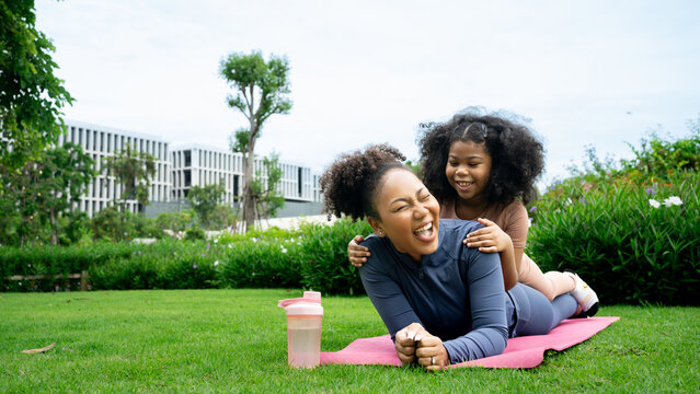 Happy African American Mother And Daughter In Sportswear Cuddling While Exercising Together Outdoor , Cute Teen Girl Kissing Her Pretty Mom Laying On Yoga Mat, City Park,out Door,  Copy Space