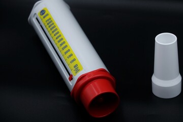 A peak flow meter with a disposable mouthpiece. Peak flow test used in the treatment of asthma. The image is isolated on a black background.