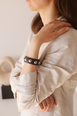 leather studded black bracelet on woman hand closeup photo on white wall background