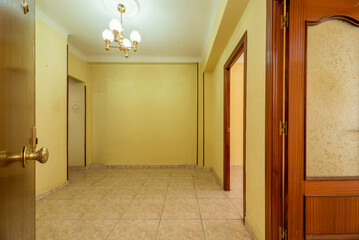 Empty room with entrance door and access doors to other rooms and light stoneware floors