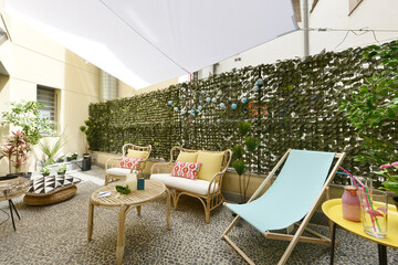 Terrace with fabric and wood hammocks, wicker furniture with fabric seats, decorative plants and stone floors