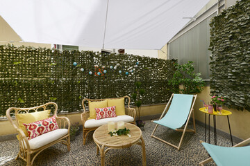 Terrace with fabric and wood hammocks, wicker furniture with fabric seats, decorative plants, white fabric awnings, stone floors, cushions and decorative ornaments