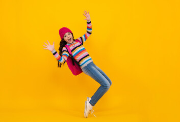 Obraz na płótnie Canvas Winter school holiday. Back to school. Teenager schoolgirl with warm hat and sweater on yellow isolated studio background. Winter school. Happy teenager, positive and smiling school girl.