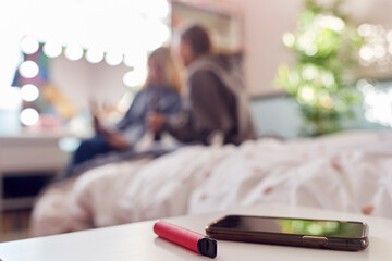 Group Of Teenage Girls In Bedroom With Vape Pen And Mobile Phone In Foreground
