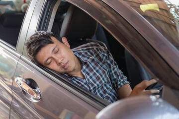 Tried man sleep in car at car park during wait someone in business or shopping time.