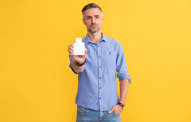 man hold pill jar on yellow background, health