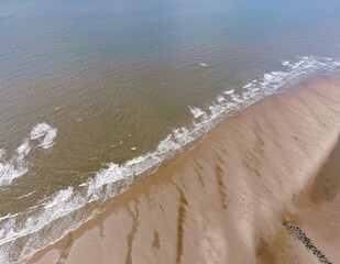 Aerial view looking down onto a beach with waves crashing. Taken in Fleetwood Lancashire England. 