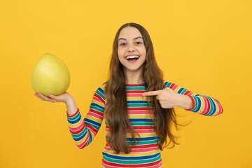Portrait of funny teen child girl hold citrus fruit pummelo or pomelo, big green grapefruit...