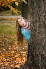 beautiful girl with long blonde hair and tongue staying near tree  in autumn park