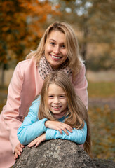 Fototapeta na wymiar Mother with daughter walking and having fun in autumn park
