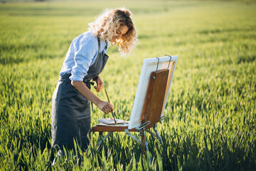 Woman artist painting with oil paints in a field