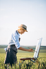 Woman artist painting with oil paints in a field