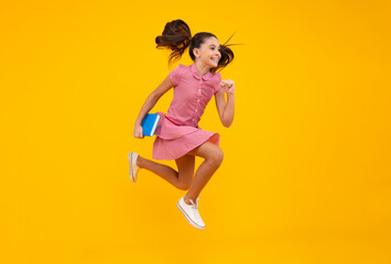 Back to school. Teenager schoolgirl with book ready to learn. School girl children on isolated yellow studio background. Happy teenager, positive and smiling emotions of teen girl.