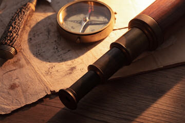 Navigation, and path finding concept. Vintage telescope, old paper and compass, on old wood table....