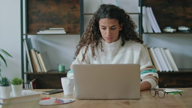 Video of concentrated beautiful business woman working with laptop in living room at home.