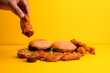 Burger and chicken legs, burger with sauce on a yellow background