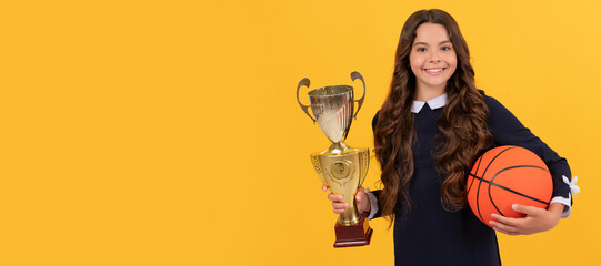 glad child hold basketball ball and champion cup on yellow background, victory. Horizontal poster...