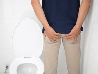 Young man has diarrhea holding his butt in toilet, diarrhea constipation. Health concept. Closeup photo, blurred. 