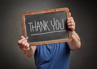 thank you  - white chalk writing on a slate blackboard held by a men, gratitude and communication concept