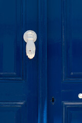 Blue door with unny white handle in the form of hand. Streets of village of Pyrgos, Tinos island,...