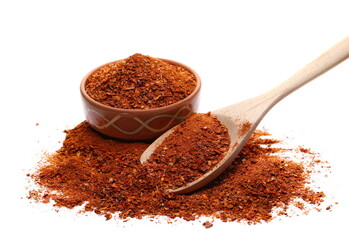 Spicy chili pepper flakes, crushed, milled red paprika pile in wooden spoon and clay pot isolated on white 