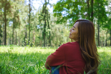 Naklejka na ściany i meble Portrait image of a young woman with closed eyes enjoying and relaxing in the park