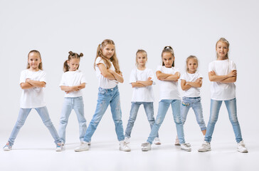 Obraz premium Dance group of happy, active little girls in jeans and t-shirts dancing isolated on white studio background. Concept of music, fashion, art, childhood, hobby