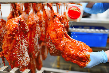 an employee of a butcher's shop or meat-packing plant sprinkles appetizing pieces of pork in tomato sauce with sesame seeds. food industry