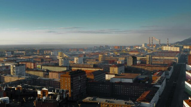 Flight above colored houses. Industrial pipes in the distance. Sunny day. 4K