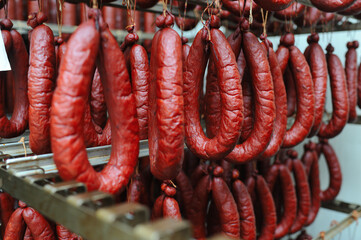 a lot of smoked sausages on the metal shelves of the racks of the meat factory. Food production