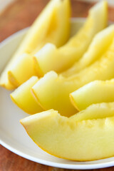 a plate full of sliced melon on a wooden board, the concept of fresh fruit and healthy food