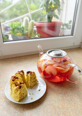 slices of homemade cake on a plate and glass teapot with stewed fruits - apples, plums and strawberries on the windowsill, concept of fresh fruits and healthy food