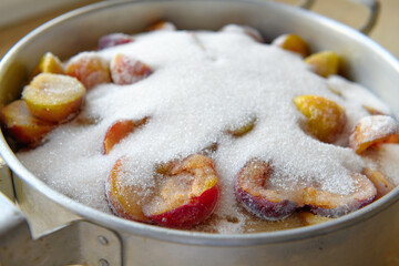 a saucepan with plums and sugar for making jam at home, the concept of preserving fruit at home,...
