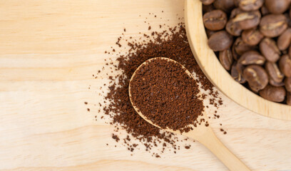 Coffee Beans in the wood bowl with coffee powder on the wooden background. Selective Focus. Copy Space.