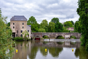 Fototapeta na wymiar View of the Sillé bridge and the Creusot grain water mill over the river Sarthe on a cloudy spring day, Fresnay-sur-Sarthe, France