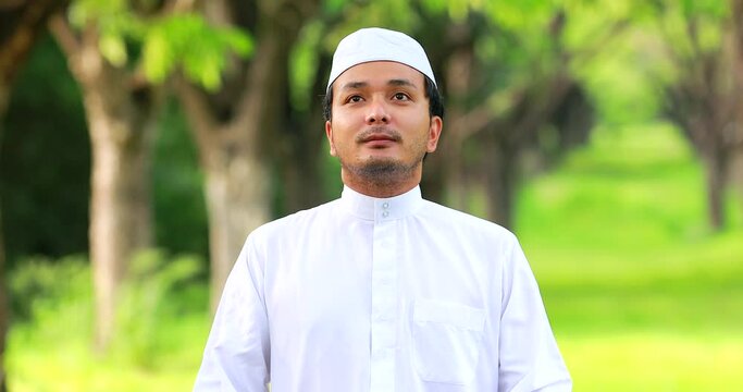 Religious muslim man traditional kandura praying outdoor at quiet nature environment sun beams.