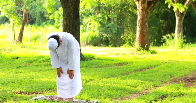 Religious muslim man traditional kandura praying outdoor at quiet nature environment sun beams.