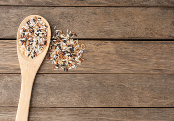Raw assorted rice on a spoon over wooden table with copy space