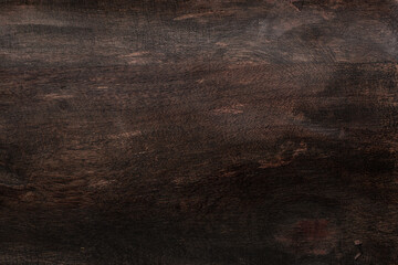 Dark brown stained wooden background with uneven rough texture