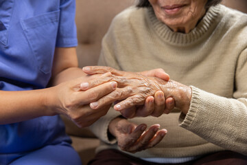 Caregiver massaging wrist of elderly woman in painful swollen gout .