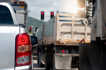 Rear side of pickup silver car on the road heading towards the goal of the trip. Traveling for work during rush hour. Environment of many wheel truck stop in the junction by red light control.