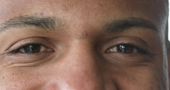 Extreme close up view young handsome smiling African man staring at camera. Happy brown-eyed guy, cropped upper face part shot. Eyesight and vision care, medical check up, eye-care services concept