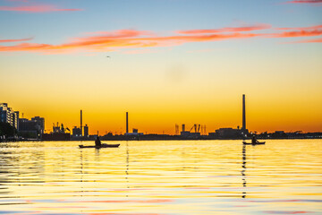 Sea kayakers paddling across Toronto's Inner Harbour just as the rising sun breaks the horizon.  Shot in summer.  Room for text.