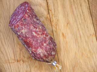 A piece of smoked sausage on a wooden cutting board.