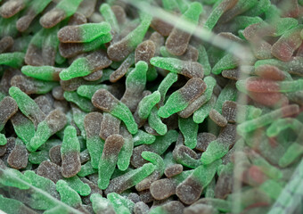 closeup of green, gray candy, healthy jelly sweets in plastic boxes on market stand in confectionery. Smart organic lifestyle, snacks. Low sugar fruit gummies. Horizontal plane