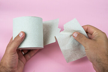 gray toilet paper in hands on a pink background