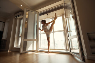 Fototapeta na wymiar young beautiful woman practices yoga in a modern bright room with large windows on a sunny day. Yoga concept at home