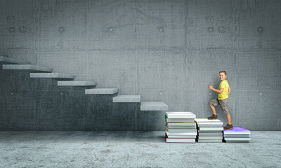 caucasian child climbs a stair made with books.