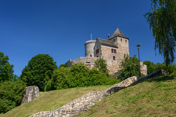 Fototapeta na wymiar Castle in Bedzin, a castle situated on a slope, is an example of defensive construction from the 14th century. Front view of the castle surrounded by greenery on a sunny summer day.