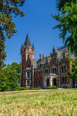 The Palace in Plawniowice, the palace and park complex from the 1980s. A magnificent building made of red brick with numerous decorations, the view on a sunny summer day.